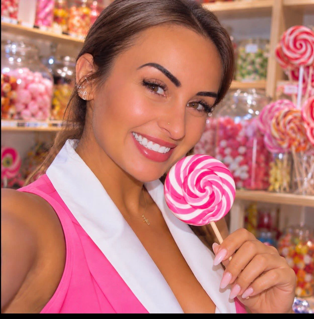 Portrait avec une sucette rose et blanche dans une boutique de bonbons